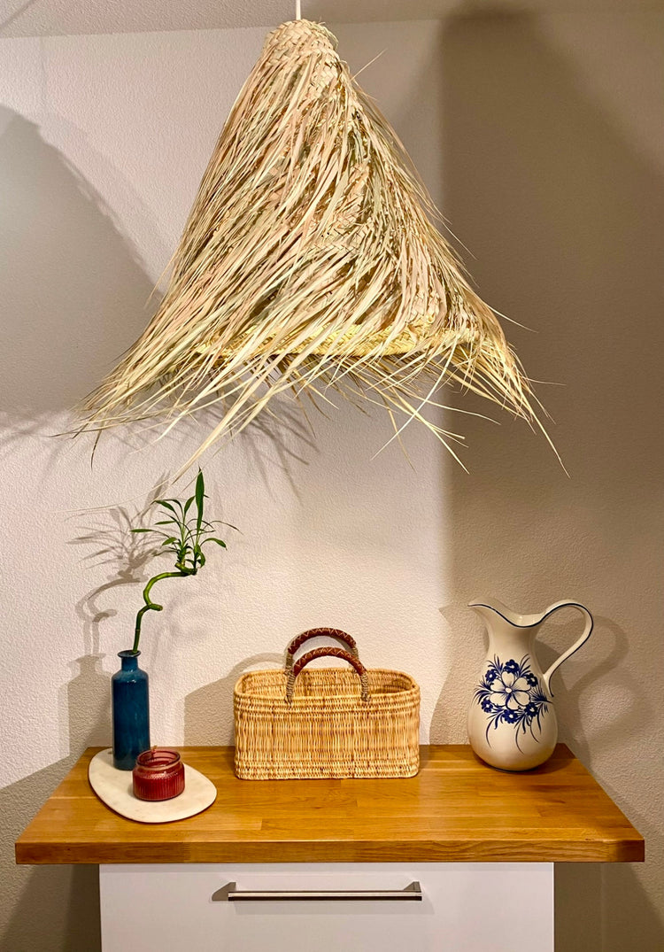 Étagère en bois élégamment décorée, mettant en valeur une collection de paniers artisanaux marocains en feuilles de palmier. La scène inclut également des vases en céramique, un miroir rond encadré de raphia, et une suspension en fibres naturelles.