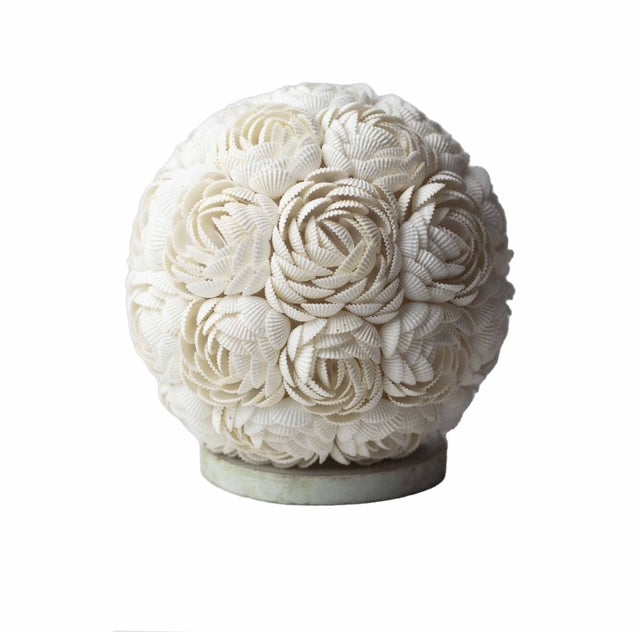 Cette lampe, réalisée à la main par des artisans talentueux, prend la forme d'un globe délicat orné de coquillages naturels. Ces coquillages, agencés en roses fines et serrées, créent un motif élégant et raffiné. Chaque élément est minutieusement disposé pour offrir une harmonie parfaite et une beauté intemporelle.

Reposant sur une base en bois, la lampe apporte une touche de chaleur et de naturel à votre intérieur, créant une ambiance douce et accueillante. 